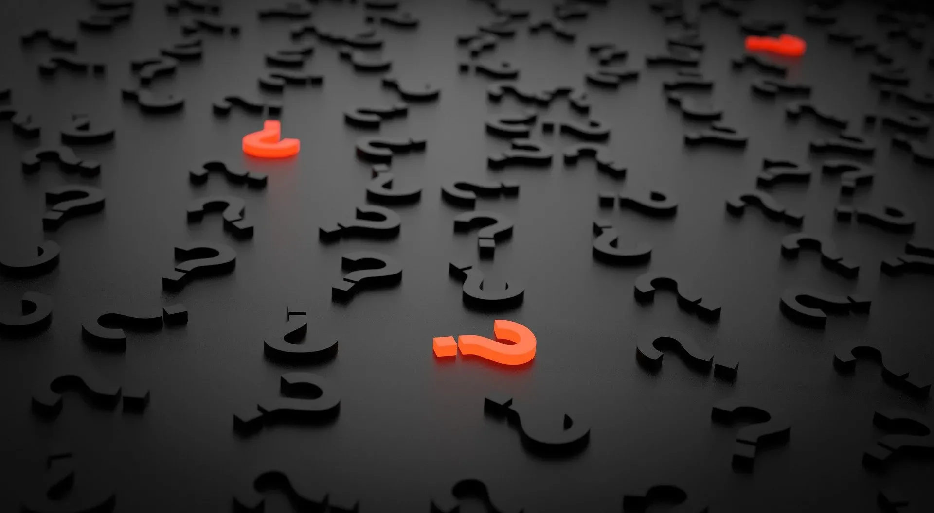3 orange question marks and lots of black question marks on a black background